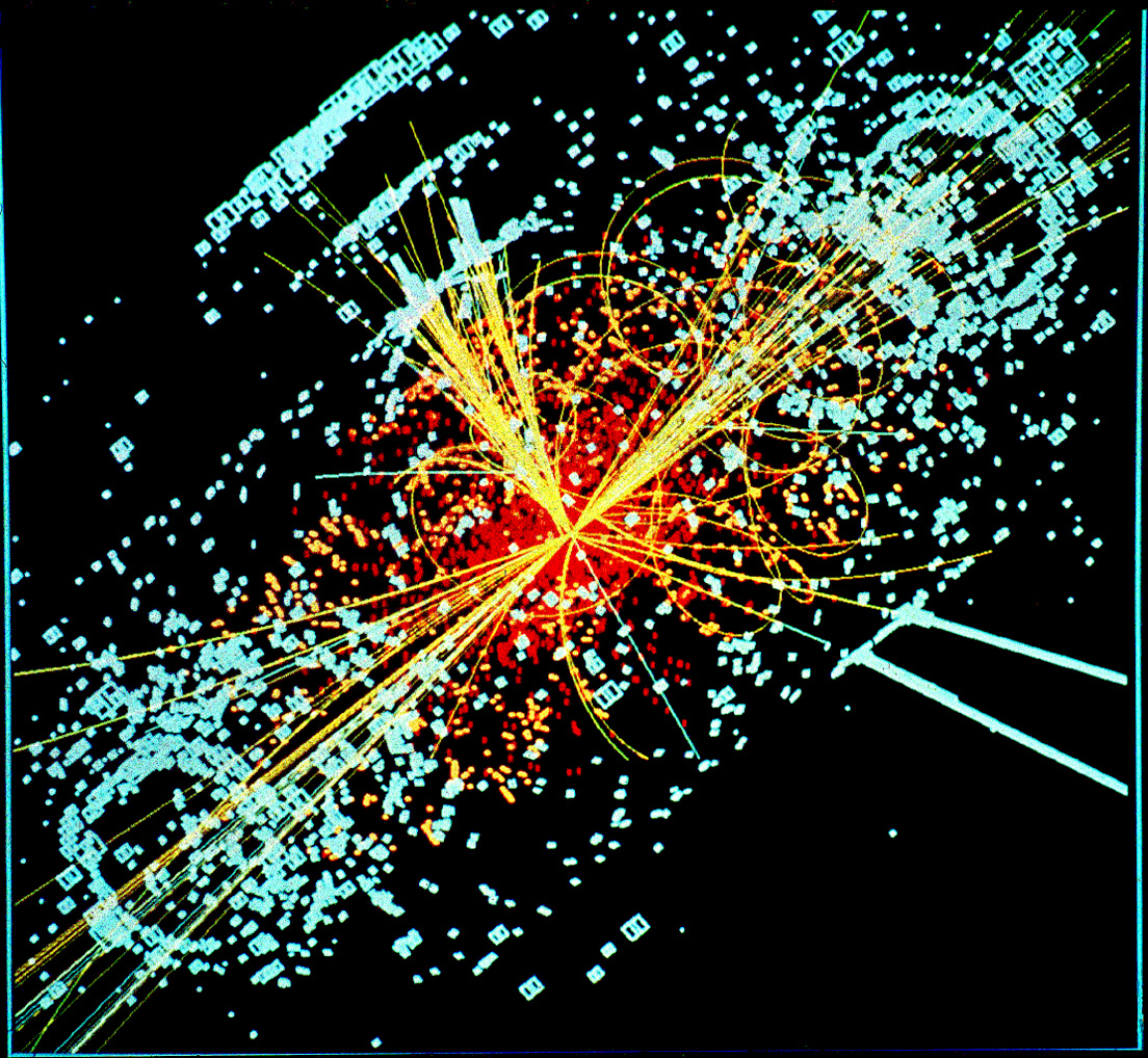 A reconstructed particle-collision event from the CMS detector: brightly coloured tracks spraying outward from a central collision point.