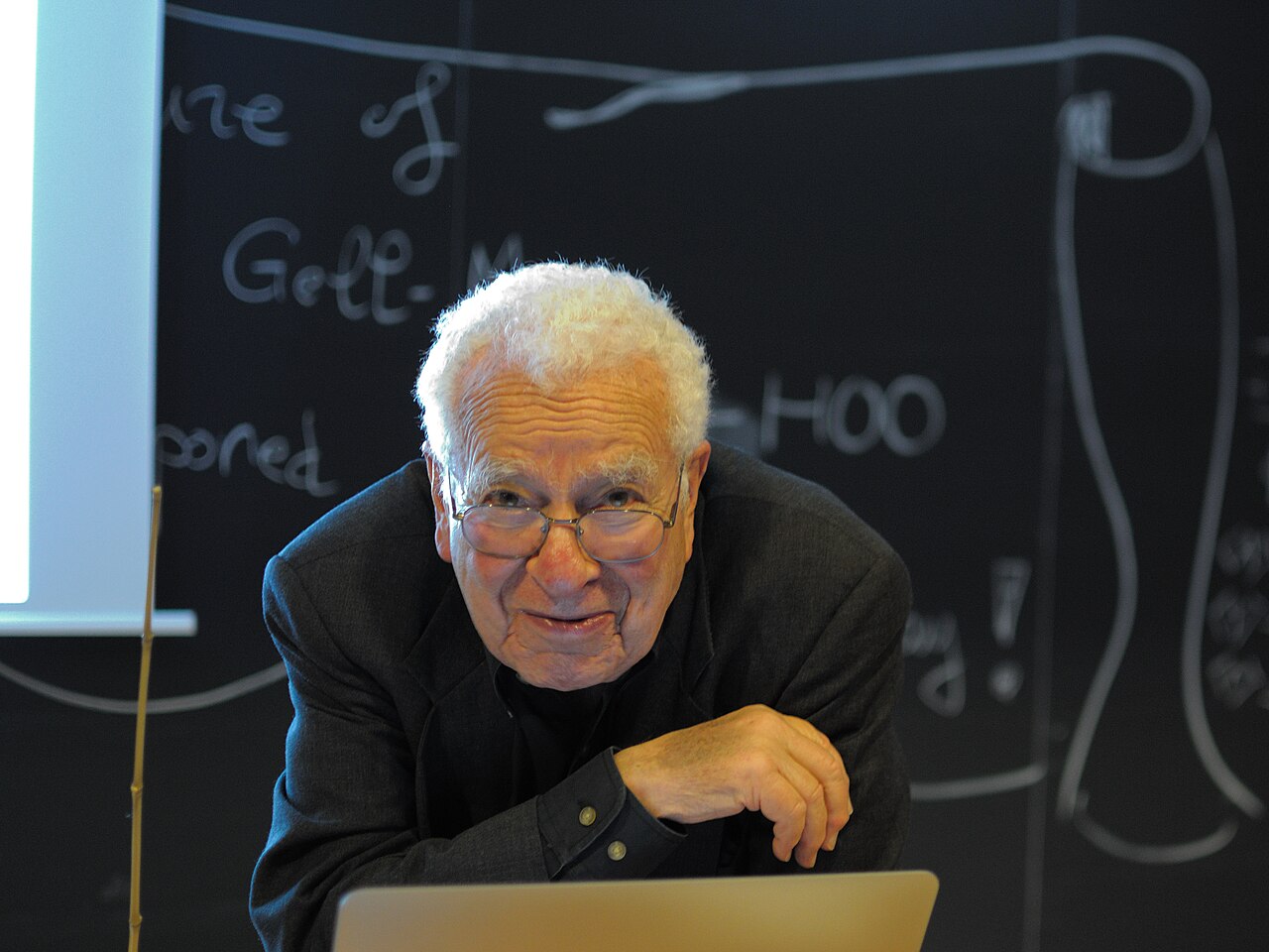 Physicist Murray Gell-Mann at a lectern.