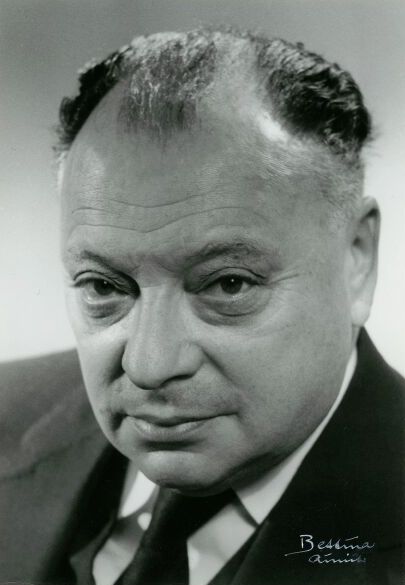 Wolfgang Pauli, round-faced, in a dark suit and tie.
