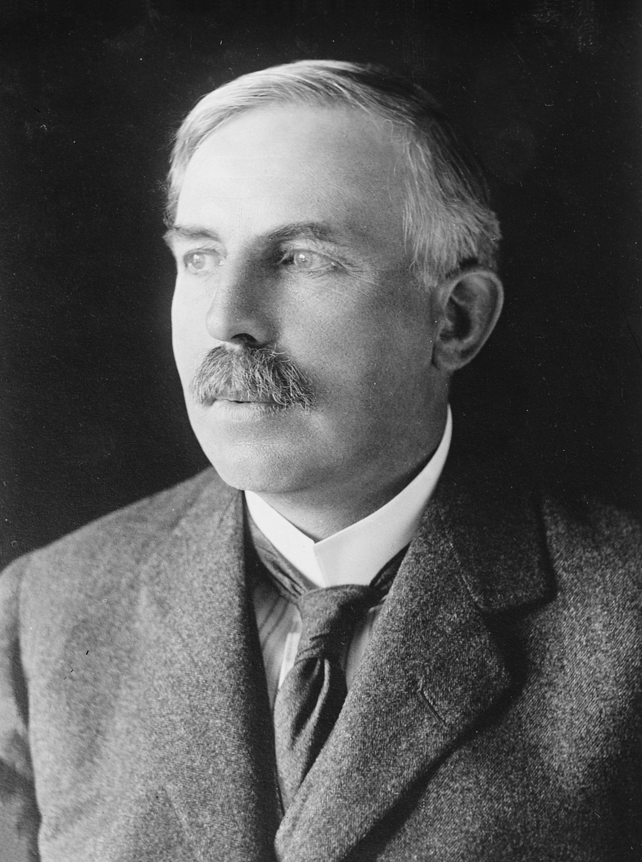Ernest Rutherford, mustached, in a suit, looking to the side.